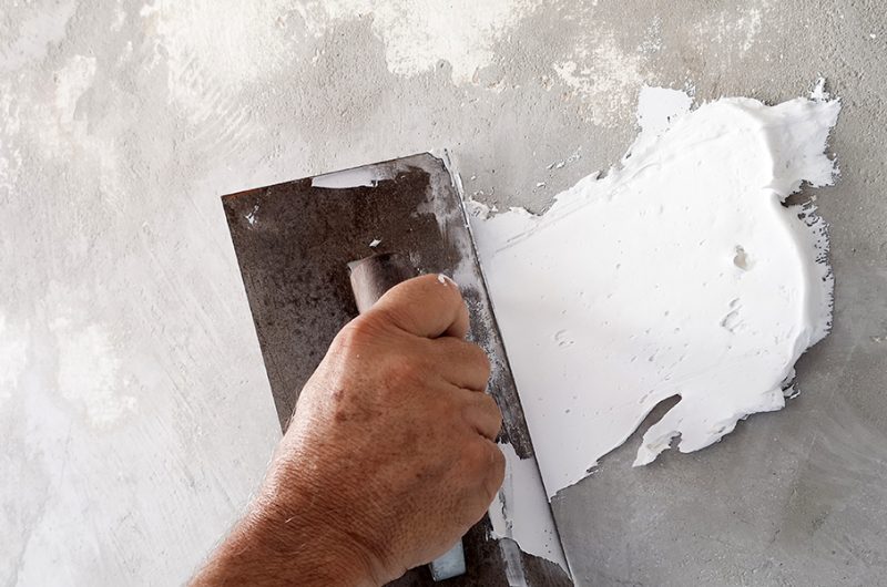 homme en train de mettre de l'enduit au plâtre sur un mur